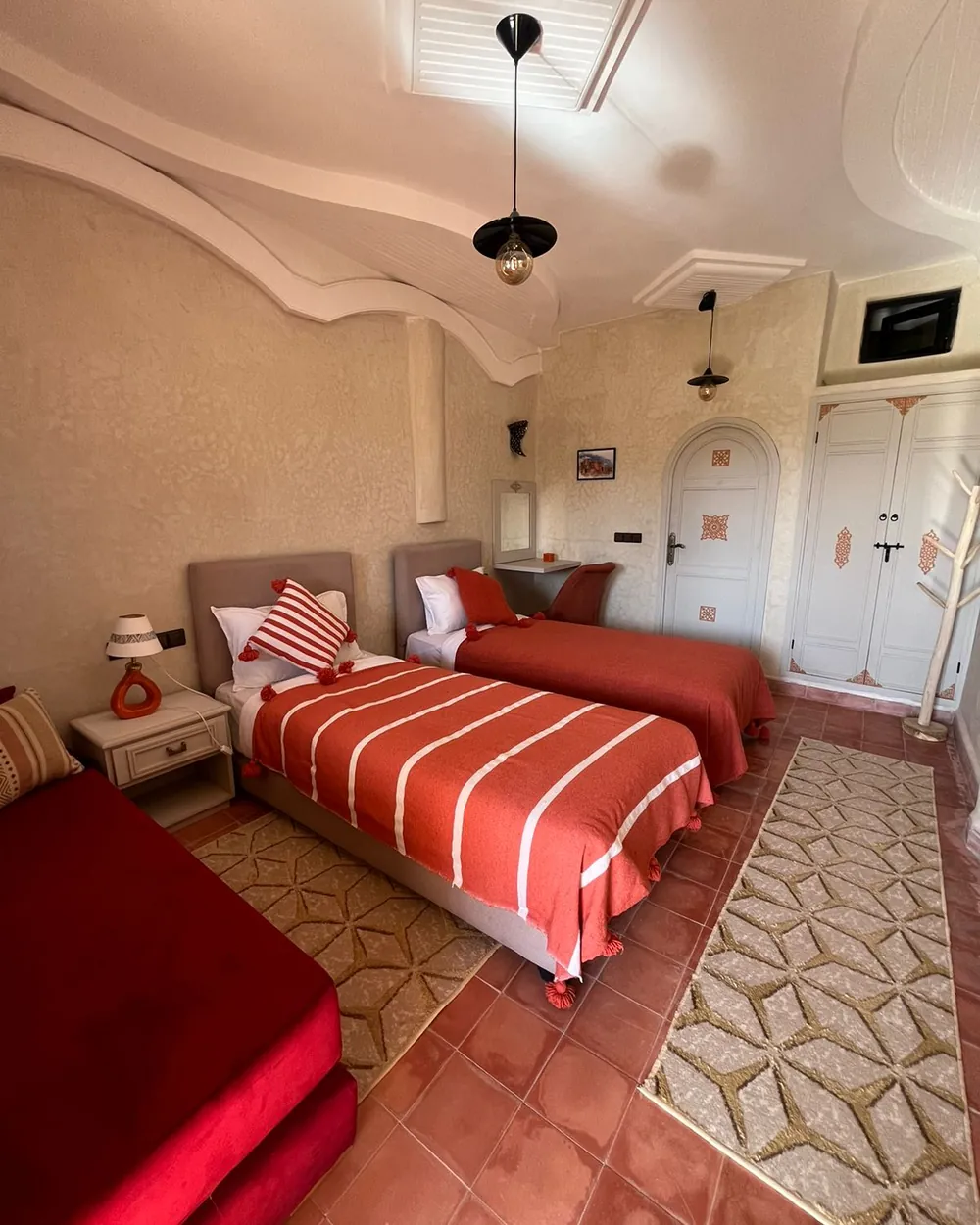 Twin room with terracotta bedding and a Moroccan tiled floor